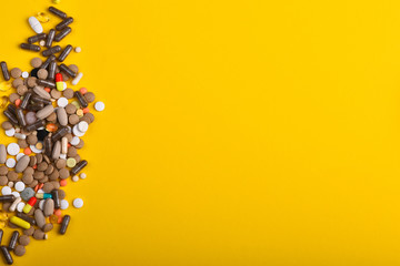 Set of colorful pills scattered on yellow background