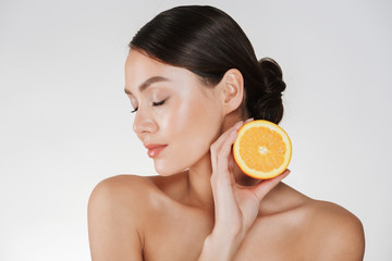 Close up image of charming woman with soft fresh skin holding juicy orange, having detox isolated over white background
