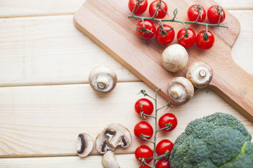 Diet, Healthy Food Cooking, Vegetarian Concept. Fresh organic cherry tomatoes, broccoli and button mushrooms on a wooden cutting board, top view