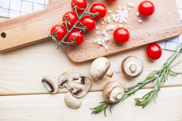 Diet, Healthy Food Cooking, Vegetarian Concept. Fresh organic cherry tomatoes, rosemary and button mushrooms on a wooden cutting board, top view