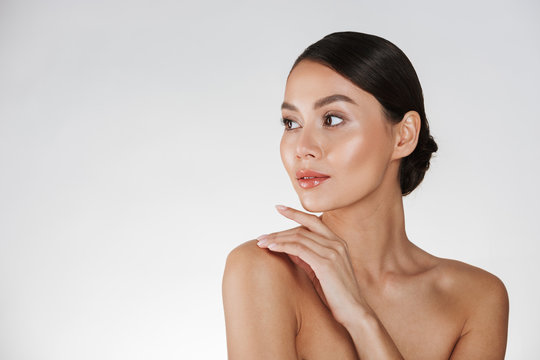 Beauty Portrait Of Feminine Young Woman Looking Away And Touching Her Nude Shoulder, Isolated Over White Background