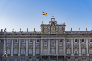 Fototapeta na wymiar Madrid, Spain Royal Palace facade with Spanish flag waving. External view of Palacio Real de Madrid in the Spanish capital, the official residence of the Spanish Royal Family.