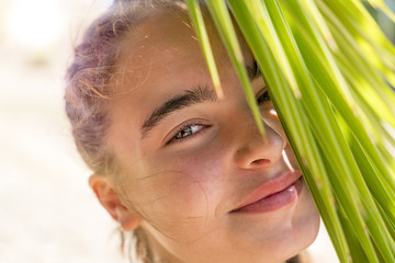 Fototapeta premium portrait of a smiling young woman with palm tree leaves