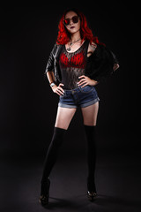 Close up of beautiful woman with tattoo wearing jeans short paint against black background.