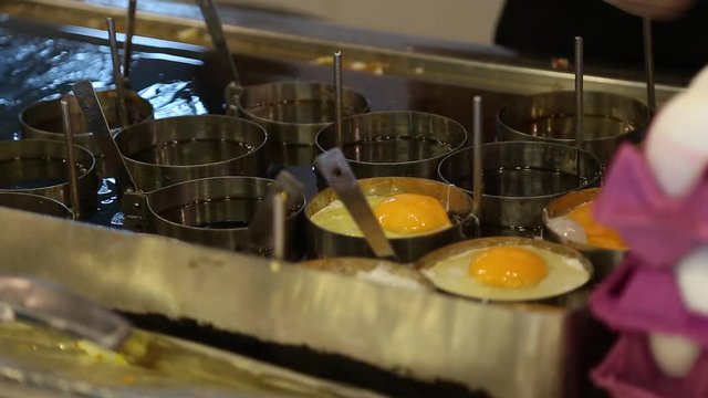 Cooking of many fried eggs at restaurant. Cook drops egg shell into pan. Real time full hd video footage.