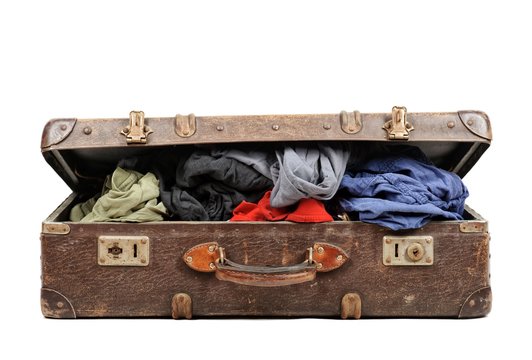 Old suitcase full of clothes isolated on white background