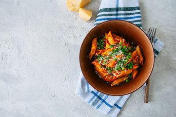 Tomato sauce and green peas penne pasta in a plate on a white stone background
