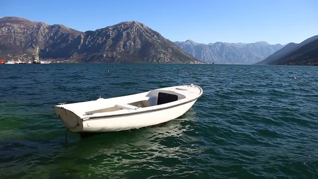 A white fishing boat rocks on the waves. Sunny day. Montenegro, Kotor Bay