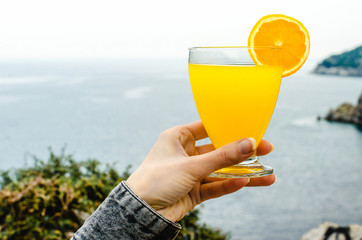 Diet. Healthy eating. Woman hand holding lemonade drink in glass  background blurred sea wild nature beach cocktail. Fresh detox vegetable orange juice. Healthy lifestyle, vegetarian food. Nutrition
