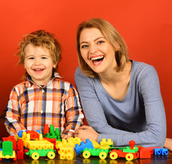 Woman and boy play on red background.