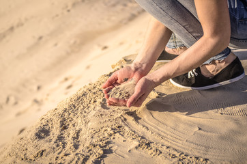 Sand in the female palms. A woman is throwing sand