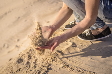 Sand in the female palms. A woman is throwing sand