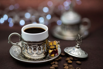 Fototapeta premium Traditional Turkish coffee in traditional metal cup on brown background with bokeh