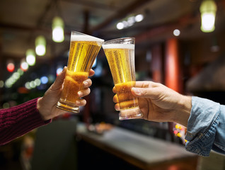 Beer glasses raised in a toast. Close-up hands with glasses.