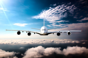 Civil wide-body plane in flight. Aircraft flying on a high altitude above the clouds. Airplane front view.