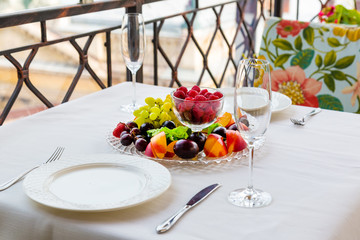 Plate of fruit with raspberries, grapes and plums is on the table for two