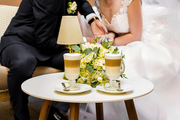 Obraz na płótnie Canvas Hands of the bride and groom for a cup of coffee. Wedding bouquet on the table.