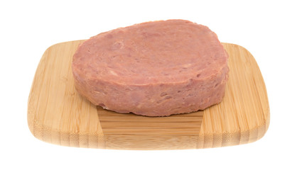 A canned ham on a wood cutting board isolated on a white background side view.