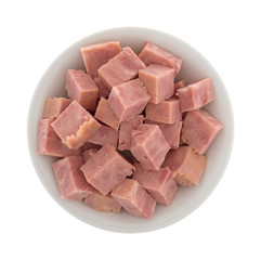 A small bowl filled with canned ham that has been cut into chunks isolated on a white background.