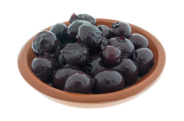 A small red clay bowl filled with canned blueberries in light syrup isolated on a white background.
