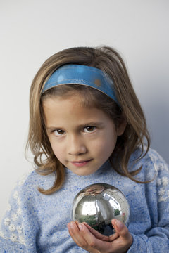 Young girl Looks Sneaky while gazing into Silver Ball