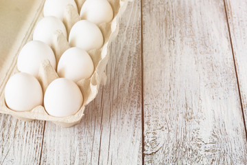Cardboard egg rack with eggs on white wooden table
