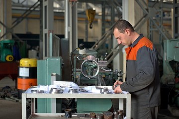 Naklejka na ściany i meble metalworking industry: factory man worker in uniform working on lathe machine in workshop