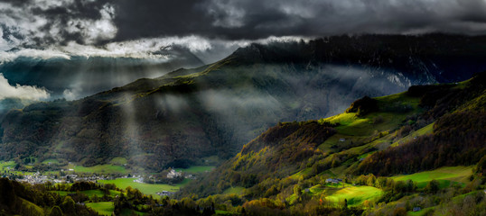 Naklejka na ściany i meble Sun rays lighting through the clouds in high Pyrenees, sunrise, green valley