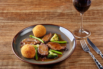 Beef cheeks in sauce with broccoli and green beans on a plate.