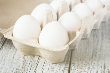 Cardboard egg rack with eggs on white wooden table