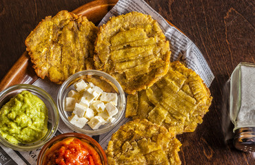 Patacones or tostones, fried plantain slices. Served with guacamole, feta cheese and tomato dip.