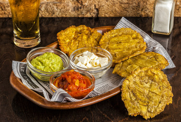 Patacones or tostones, fried plantain slices. Served with guacamole, feta cheese and tomato dip.