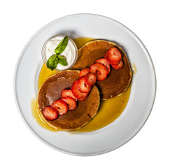 American breakfast with pancakes, strawberries and syrup.