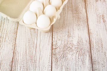Cardboard egg rack with eggs on white wooden table