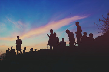 Silhouettes of people standing on the hill watching city on dusk