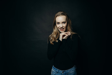 Fototapeta premium Crazy day. Waist up portrait of beautiful shocked young woman wears black turtleneck sweater, looks with a puzzled expression as hears something unexpected, has problems or troubles in life. Tiredness