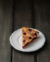 A piece of cherry pie on a white vintage plate on a wooden background. Copy Space. View blank space for text.