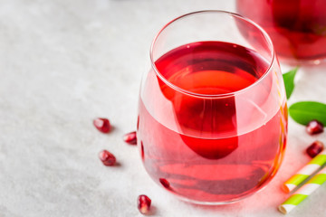 A glass of fresh pomegranate juice on white marble background. Selective focus, copy space.