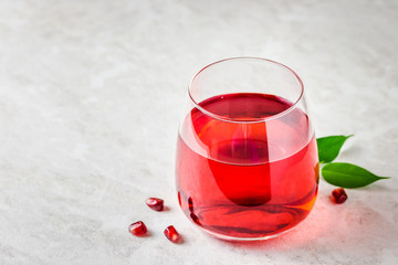 A glass with pomegranate juice on white marble background. Selective focus, copy space.