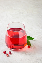 A glass of pomegranate juice on white marble background. Selective focus, copy space.