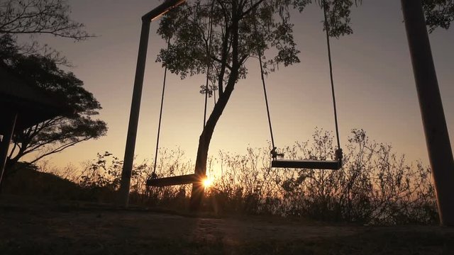 Slow motion, Empty swing set swing, silhouette at sunset.
