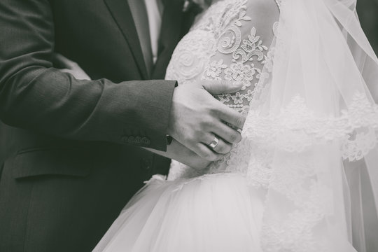 Closeup of hands of caucasian wedding couple. Black and white photography.