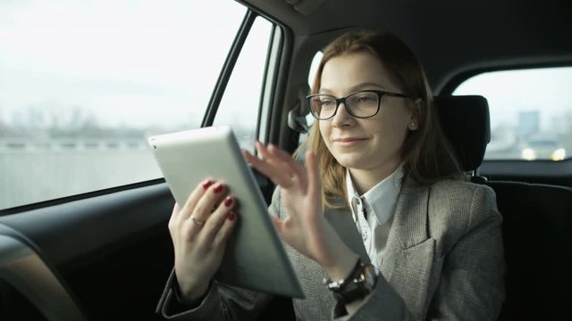 Businesswoman Smiling While Using a Tablet in the Car