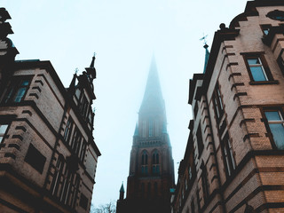 church tower between houses on a foggy day