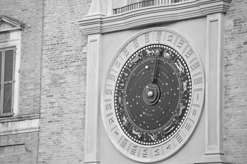 Detail of a bell tower that shows an ancient sundial in black and white