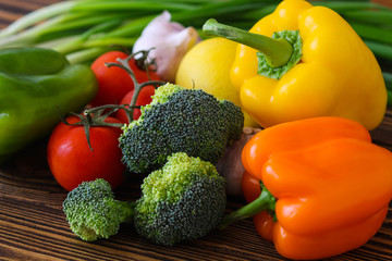 Fresh tasty vegetables. Tomatoes, sweet peppers, broccoli, garlic, dill, parsley. On a wooden background.