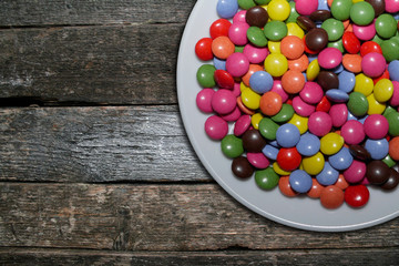 sweet colorful candies on plate on plank