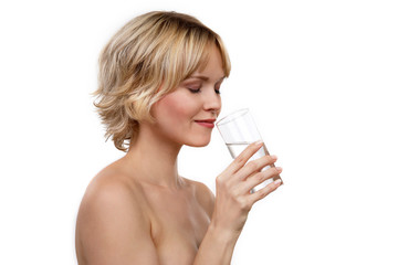 Blonde Frau mit einem Glas Wasser lächeklt