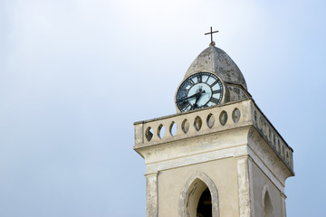 Bell tower of a church with clock with gray sky in the background San Pietro in Amantea (calabria)
