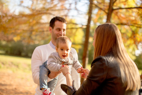 Happy young parents with baby boy in autumn park